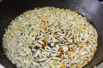 The process of frying the onions in a hot pan in oil