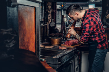 Bearded chef cooking beef steak on a kitchen in a restaurant.