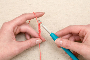 Hands Crocheting a Chain of Orange Yarn