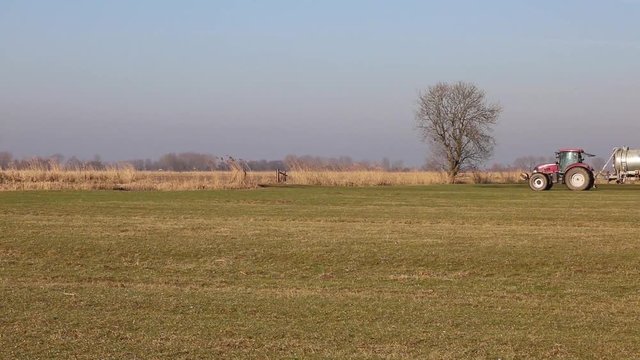 Bauer mit Traktor d&uuml;ngt sein Feld