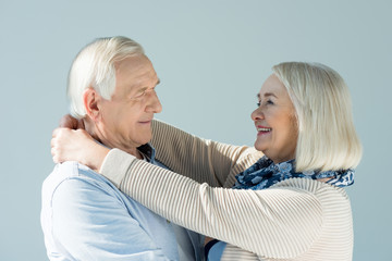 portrait of smiling senior woman hugging husband on white