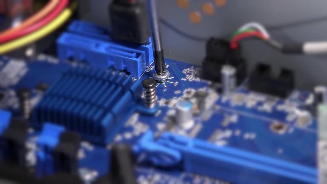 Screwdriver unscrew bolt on computer motherboard. Computer warranty works