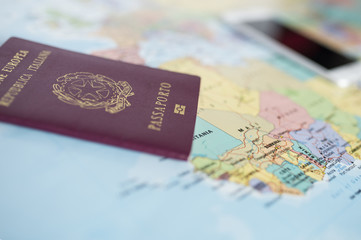 (travel concept) Close-up view of a European Union passport and a blurred smartphone on a defocused geographical World map.