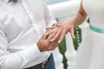 Obraz na płótnie Canvas Groom putting a ring on bride's finger during wedding ceremony