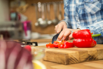 Chef chopping bell pepper on cutting board. Woman cooking.