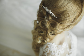 Hair stylist makes the bride a wedding hairstyle with fresh flowers