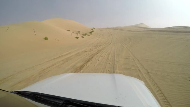 4x4 SUV car driving through the sand dunes in the desert of abu dhabi