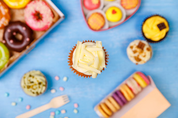 Cupcake with white chocolate, Donuts and Macaroons. Sweet dessert. Cakes with buttercream. Almond macaron cookies. Delivery box.