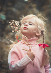 Little blonde girl blowing dandelion.