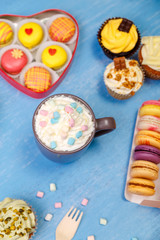 Macaroons, cupcakes and donuts. Mug with whipped cream and marshmallows. Almond macaron cookies. Sweet dessert.