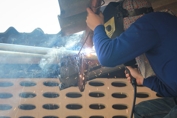 Steel welder working on bamboo scaffolding.