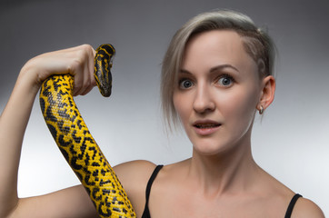 Blond woman holding yellow snake