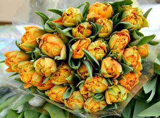 The big bouquet of orange tulips lies on a counter for sale