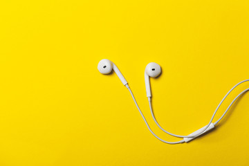 White headphones on a yellow paper background