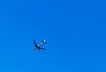 Fototapeta na wymiar Aircraft is flying in blue cloudy sky over the sea.