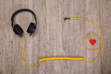 Headphones with red heart. Love listening music. Sound earphones with yellow cable on wooden rustic background.