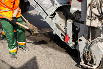 Road workers repair work. work sleeps shovel the material into the machine.