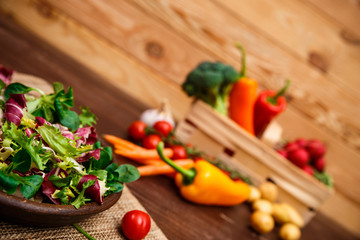 Provence salad. Leaves of endive or chicory, lamb and rose salad. Cherry tomato, pepper and carrot. Raw vegetables. On wooden table.