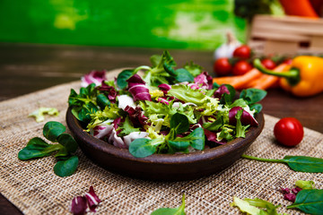 Provence mix salad. Leaves of endive or chicory, lamb and rose salad. Raw vegetables. On wooden table.