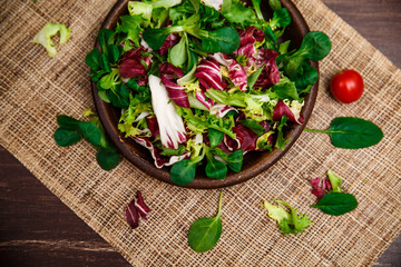 Provence salad. Leaves of endive or chicory, lamb and rose salad. Cherry tomato. Raw vegetables. On wooden table.