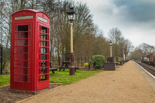 Old fashioned red British phone box on a vintage railway station platform
