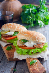 Homemade hamburger with beef, onions, tomatoes, salad and cheese on a wooden board, selective focus