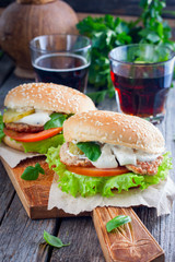 Homemade hamburger with beef, onions, tomatoes, salad and cheese on a wooden board, selective focus