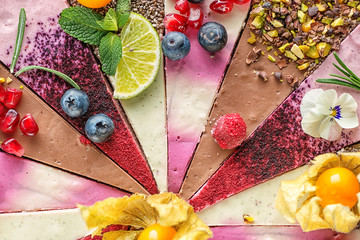 Raw vegan cakes with fruit and seeds, decorated with flower, product photography for patisserie. colourful pieces of raw dessert