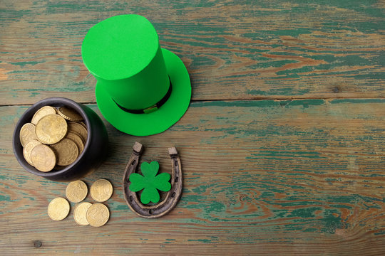 Happy St Patricks Day leprechaun hat with gold coins and lucky charms on vintage style green wood background. Top view