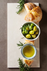 Olivier oil with fresh herbs and bread. Light background. Italian and Greek national food. Top view