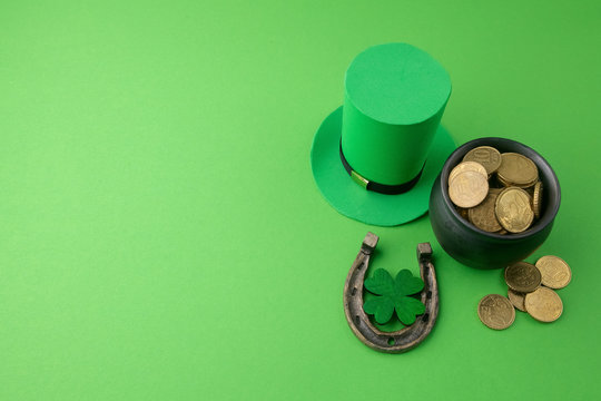 Happy St Patricks Day leprechaun hat with gold coins and lucky charms on green background. Top view.