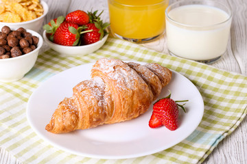 Breakfast with croissants, milk, orange juice and cornflakes