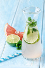Detox fruit infused water. Refreshing summer cocktail with lime graipfruit and mint.  Wood background
