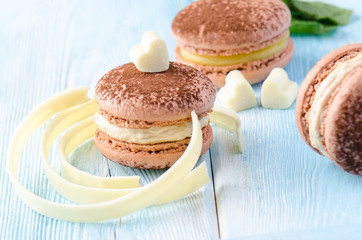 coffee macaroons with white chocolate in the shape of a hearts on blue wooden backgroundю Close up