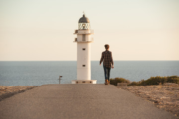 woman walking by a lighthouse