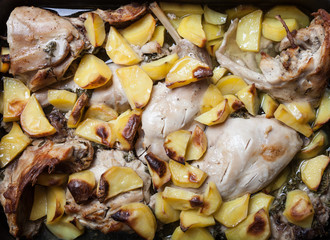 Prerared rabbit meat with potato on a rustic style background