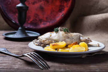 Prerared rabbit meat with potato on a rustic style background. Selective focus
