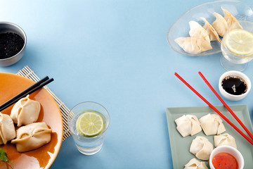 Asian dumplings with sauces and drinks on blue background. Top view with copyspace