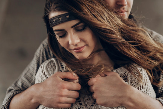 stylish hipster couple gently hugging. man in hat  embracing boho woman in knitted sweater. atmospheric sensual moment. rustic fashionable look.