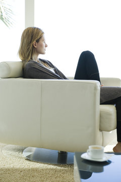Woman relaxing in armchair, looking out window