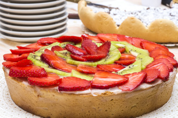Cake with strawberry and kiwi, dishes in the background
