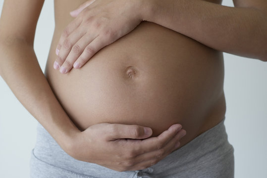 Pregnant woman holding her belly, cropped
