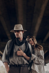 Romantic gypsy woman in stylish boho clothes and white dress hugging handsome cowboy man in white hat and scarf