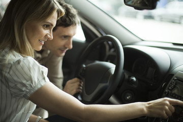 Couple checking out a car interior in dealership showroom

