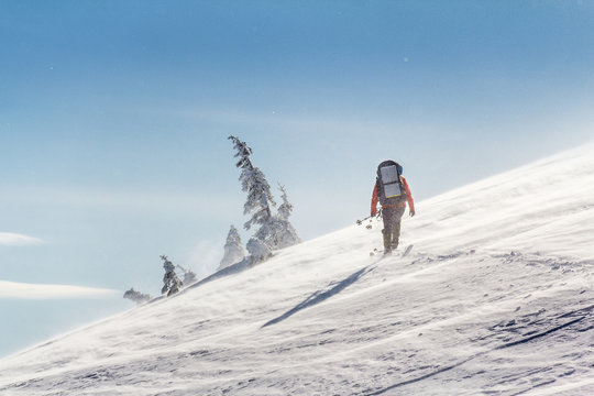 Alone skier hiking with a backpack in winter mountains slopes