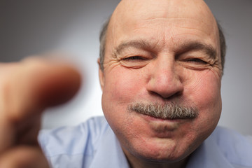 Elderly man barely holding back laughter, puffing out his cheeks. breath holding