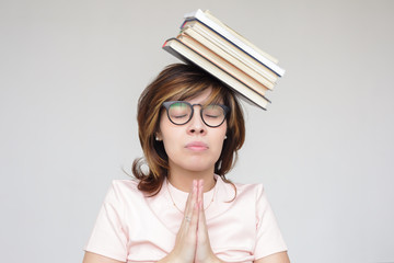 Girl meditates with a pile of books on head. Preparing for the exam, or reading books