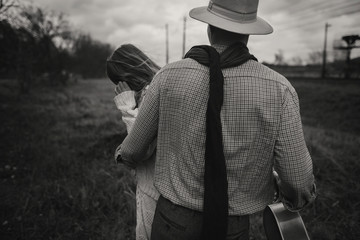 boho gypsy woman and man in hat embracing in windy field.stylish hipster couple dancing. atmospheric motion moment. fashionable look. rustic wedding concept. black white photo