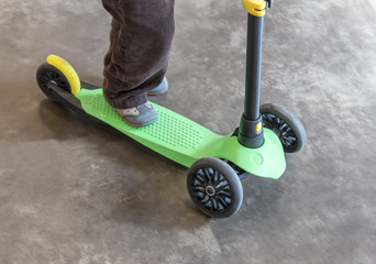 Close up of boy riding scooter outside
