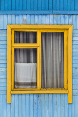 Old yellow window with curtains on blue wooden wall